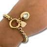 Gold bracelet with charms on a wrist against a neutral background
