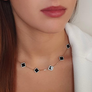 Necklace with clover-shaped pendants worn by a person against a neutral background