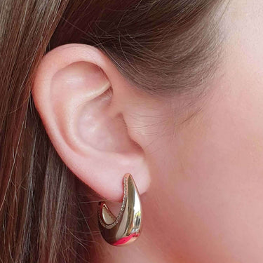 Gold hoop earring worn by a person with a blurred background