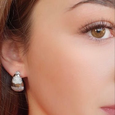 Close-up of a woman wearing a diamond earring with a pink blouse.