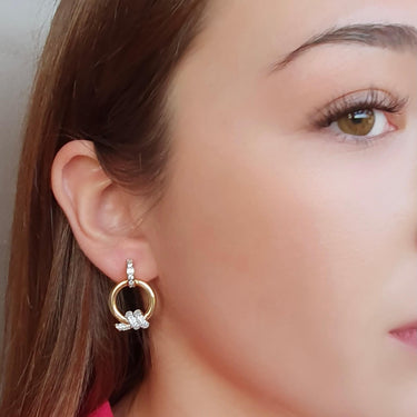 Close-up of a woman wearing gold hoop earrings with small pearls.