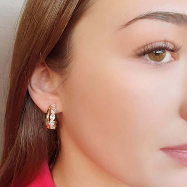 Close-up of a woman wearing a small hoop earring with a blurred background