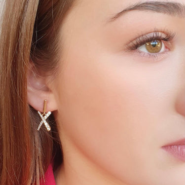 Close-up of a woman wearing gold earrings with a pink top.