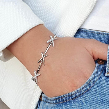 Person wearing a silver bracelet on a blurred background