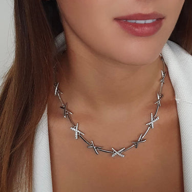 Silver necklace worn by a person with a neutral background