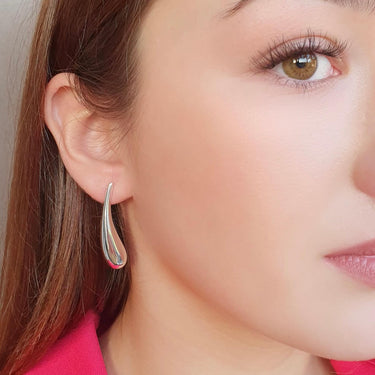 Close-up of a woman wearing a silver hoop earring with a neutral background