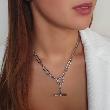 Silver chain necklace with a pendant worn by a person against a neutral background