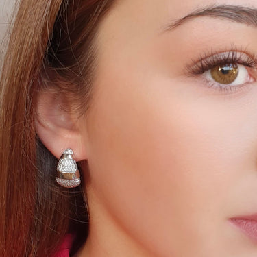 Close-up of a woman wearing a diamond earring with a pink blouse.