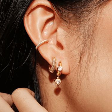Close-up of an ear wearing gold hoop earrings with a diamond.