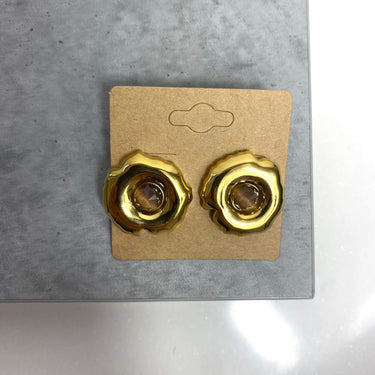 Pair of gold earrings on a cardboard backing against a gray background