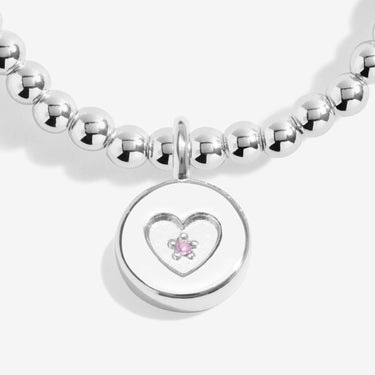 Silver beaded bracelet with a heart-shaped charm featuring a pink gemstone on a white background