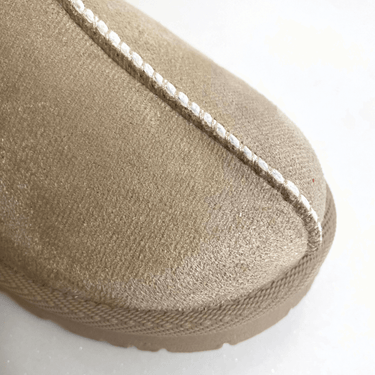 Close-up of a beige slipper with white stitching on a white background