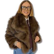 Person wearing a brown fur coat with a plain background