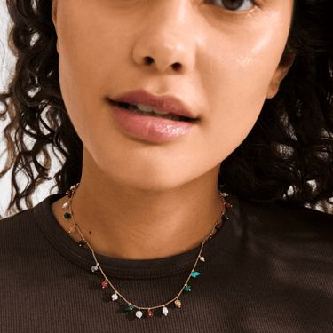 Close-up of a woman wearing a delicate necklace with colorful beads.