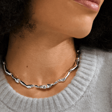 Silver necklace worn by a person with a neutral background