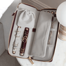 Open jewelry case with watches and jewelry on a white surface