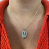 Silver necklace with a pendant worn by a person wearing an orange sweater.