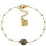 Gold bracelet with a central stone on a white background