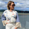 Woman wearing a floral blouse and sunglasses with a scenic background