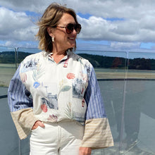 Woman wearing a floral blouse and sunglasses with a scenic background