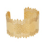 A wide, open cuff bracelet in textured yellow gold with a hammered finish and vertical slit edges, shown on a plain light gray background.