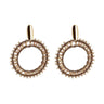 A pair of gold-toned dangle earrings with circular openwork designs, accented by small clear beads and a polished oval post, shown on a light gray background with a soft reflection below.