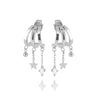 A pair of silver huggie hoop earrings with dangling star and bead charms, shown on a light gray background with a soft reflection below.