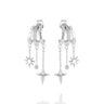 A pair of silver huggie hoop earrings with dangling star and chain charms, shown on a light gray background.