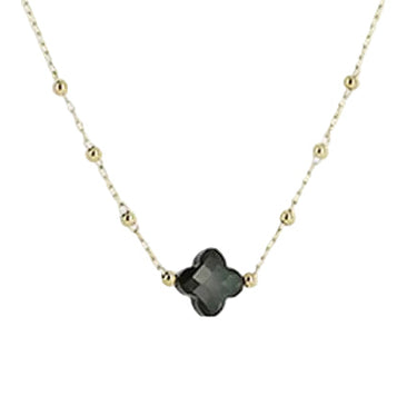 A delicate gold chain necklace featuring a central four-petal flower charm in a smoky black glass finish, suspended against a plain light gray background.