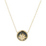 A gold chain necklace with a circular pendant featuring a dark mother-of-pearl background and a gold compass star motif with small clear crystals, shown on a light gray background.
