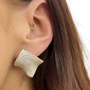 Gold earring worn by a person with long hair