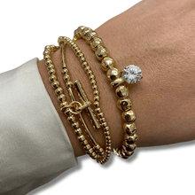 Gold beaded bracelets on a wrist with a neutral background