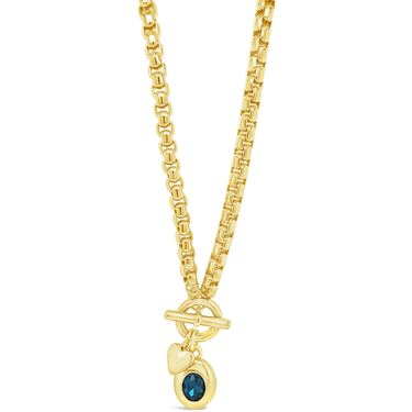 Gold necklace with a blue gemstone pendant on a white background