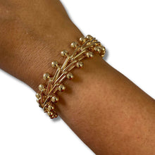 A gold-toned beaded branch-style cuff bracelet worn on a person's wrist, shown against a plain white background.
