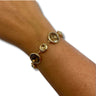 A gold-toned bracelet with three oval faceted clear gemstones displayed on a person's wrist against a plain white background.