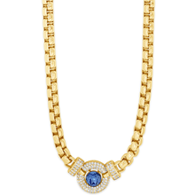Gold necklace with a blue gemstone and clear stones on a white background