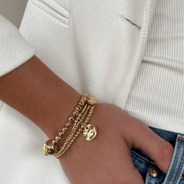 Gold bracelet on a wrist with a neutral background