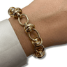 Gold chain bracelet on a wrist with a neutral background