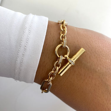 Gold bracelet with charms on a wrist against a white background