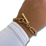 Gold bracelet on a wrist with a white shirt sleeve, on a white background