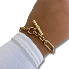 Gold bracelet on a wrist with a white shirt sleeve, on a white background