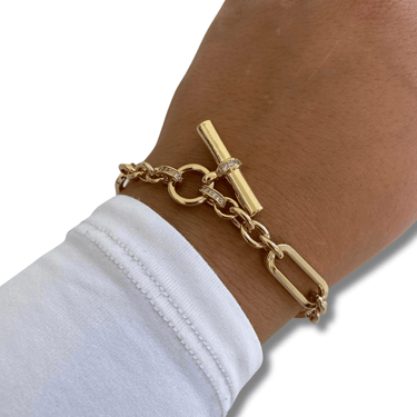 Gold bracelet on a wrist with a white shirt sleeve, on a white background