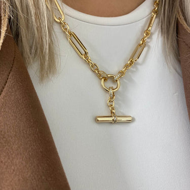Gold chain necklace with a clasp charm worn by a person on a white background
