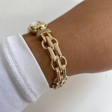 Gold chain bracelet on a wrist with a white shirt cuff.