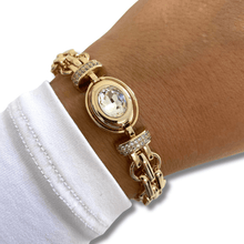 Gold bracelet with a large gemstone on a wrist against a white background