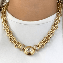 Gold chain necklace with a central gemstone on a white background