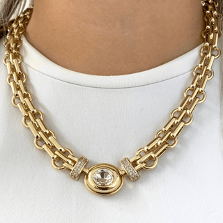 Gold chain necklace with a central gemstone on a white background