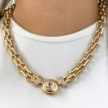 Gold chain necklace with a central gemstone on a white background