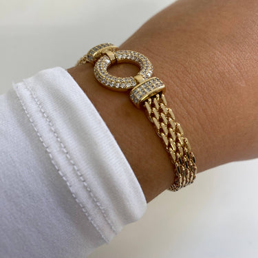 Gold bracelet with chain design on a wrist against a white background
