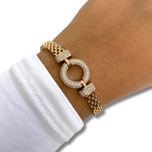 Gold bracelet with circular design worn on a wrist against a white background